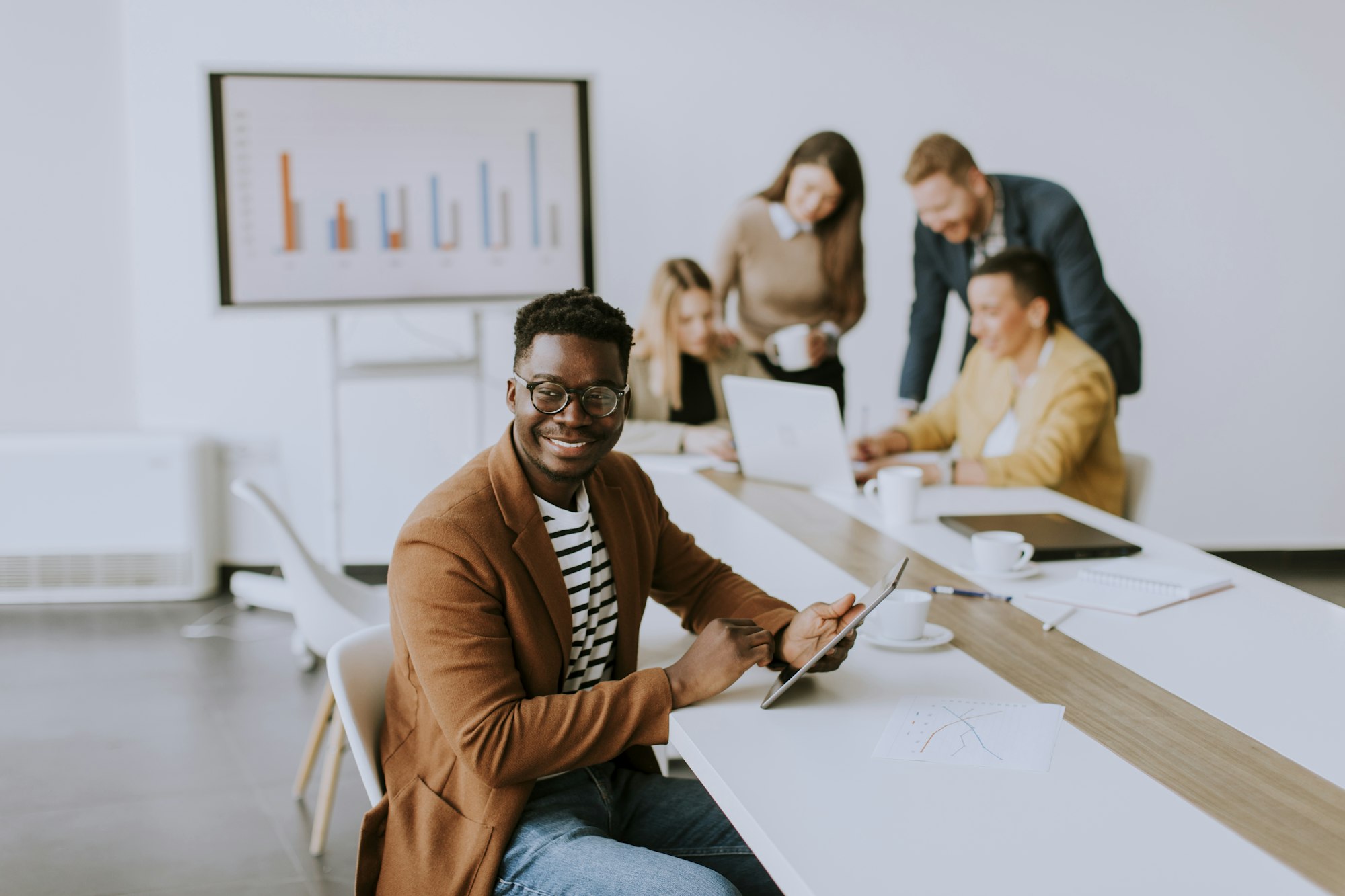 Young African American business man working with digital tablet in front of his coworkers